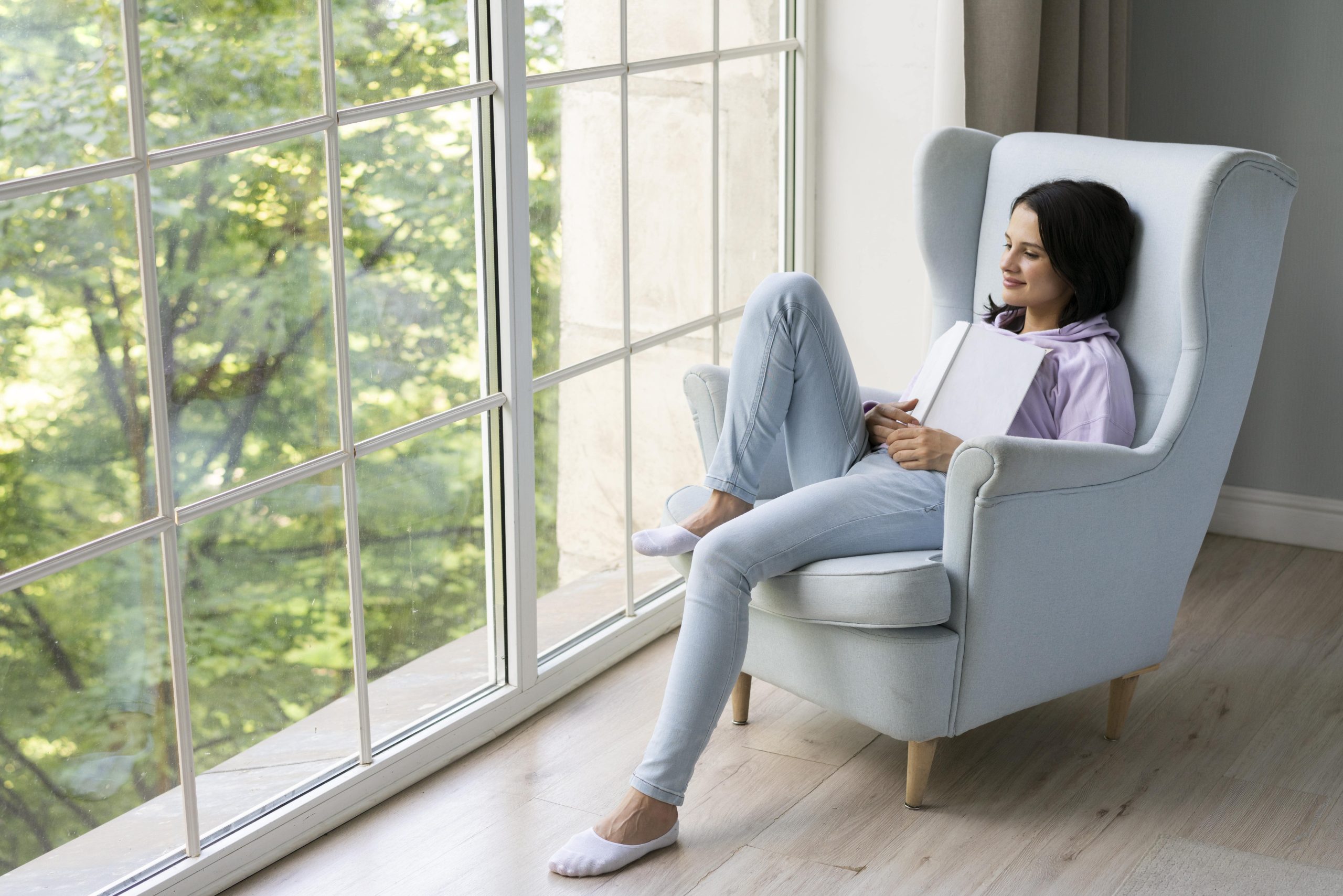 young-woman-holding-her-book-while-looking-out-window-min